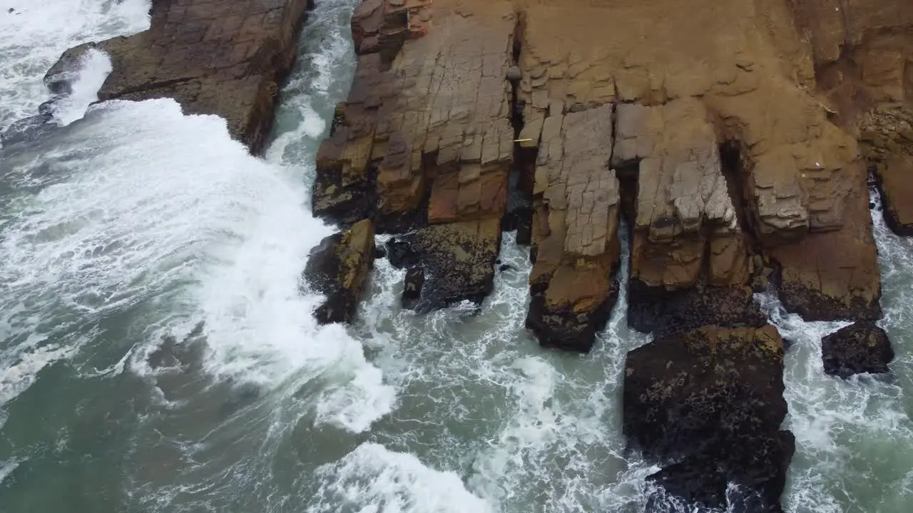 Drone footage of a rocky outcrop on a beach in Lima Peru