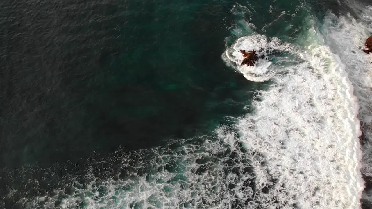 Aerial view of waves splashing on the rocks in Uluwatu Bali