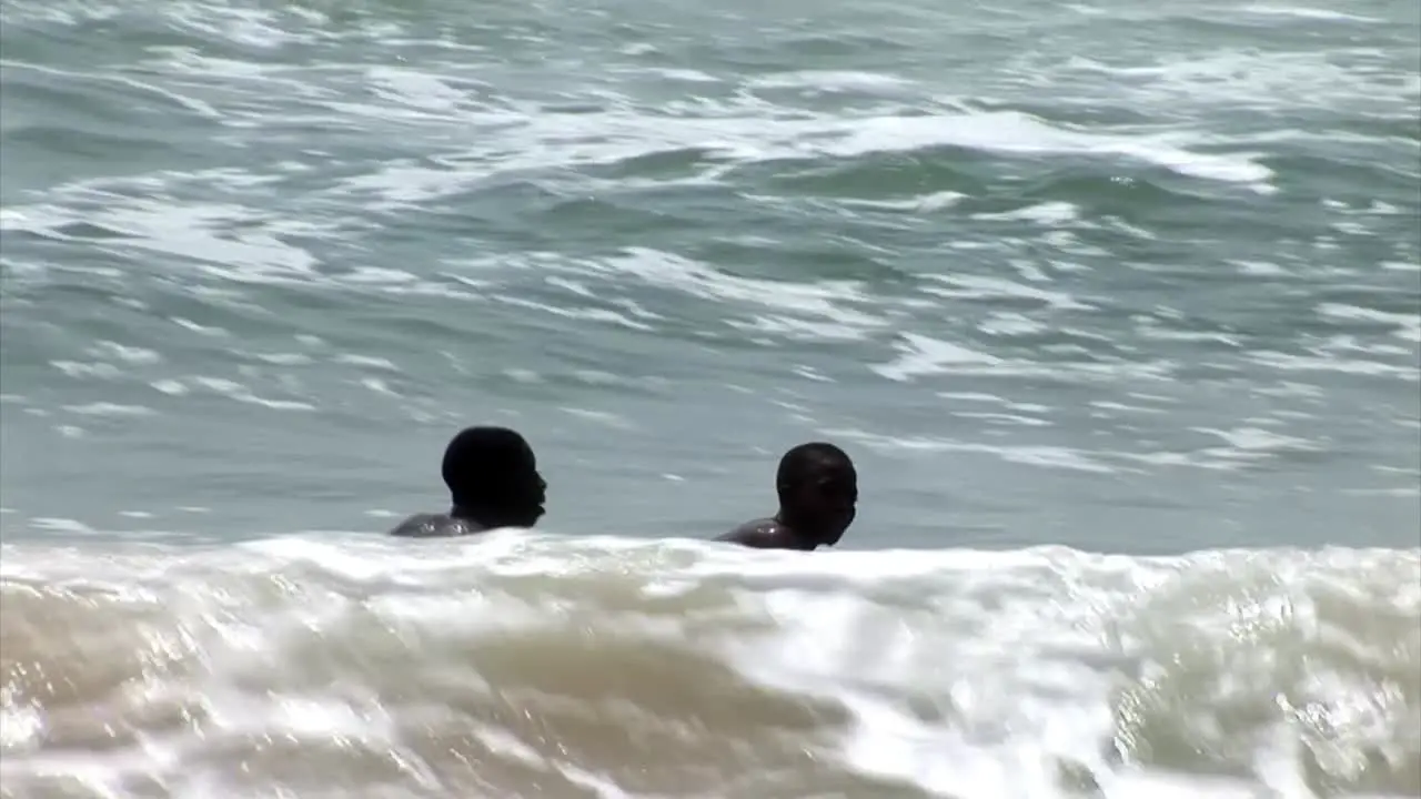 Two nigerian kids try to catch a wave with a makeshift surf board