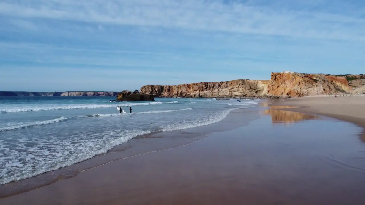 perfect white sandy beach in tonel near sagres  some surfers hit the water