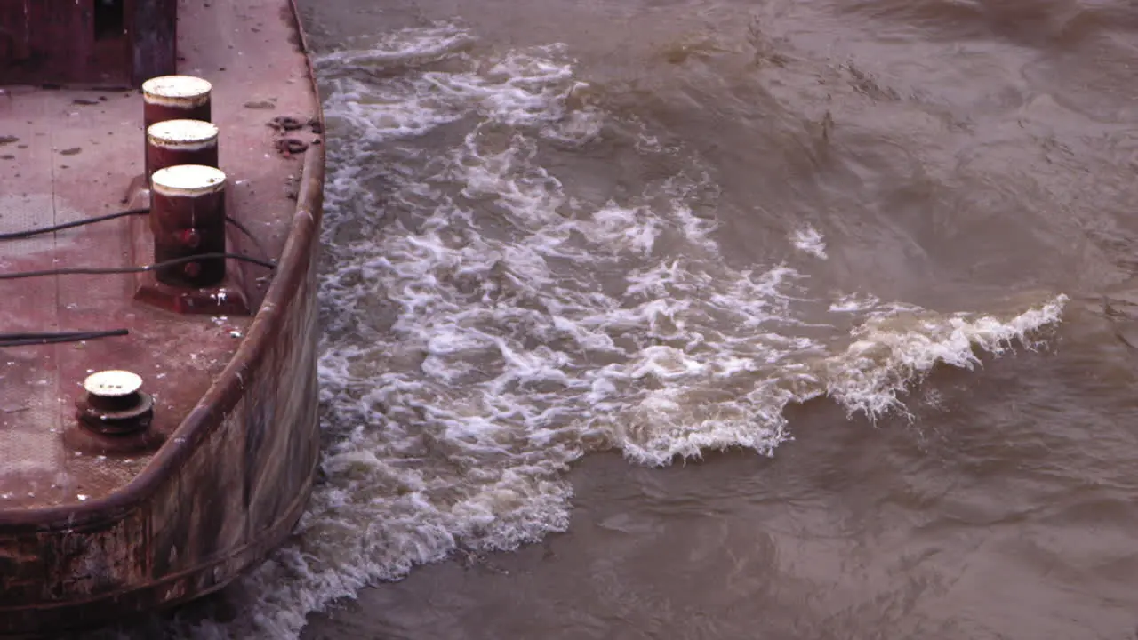 Slow motion footage of the front of ship that is moving upstream on the Seine river with waves bouncing off the hull