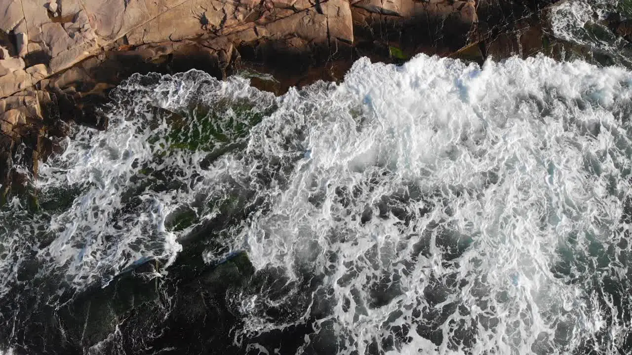 Sea foam waves crashing into rocky shore