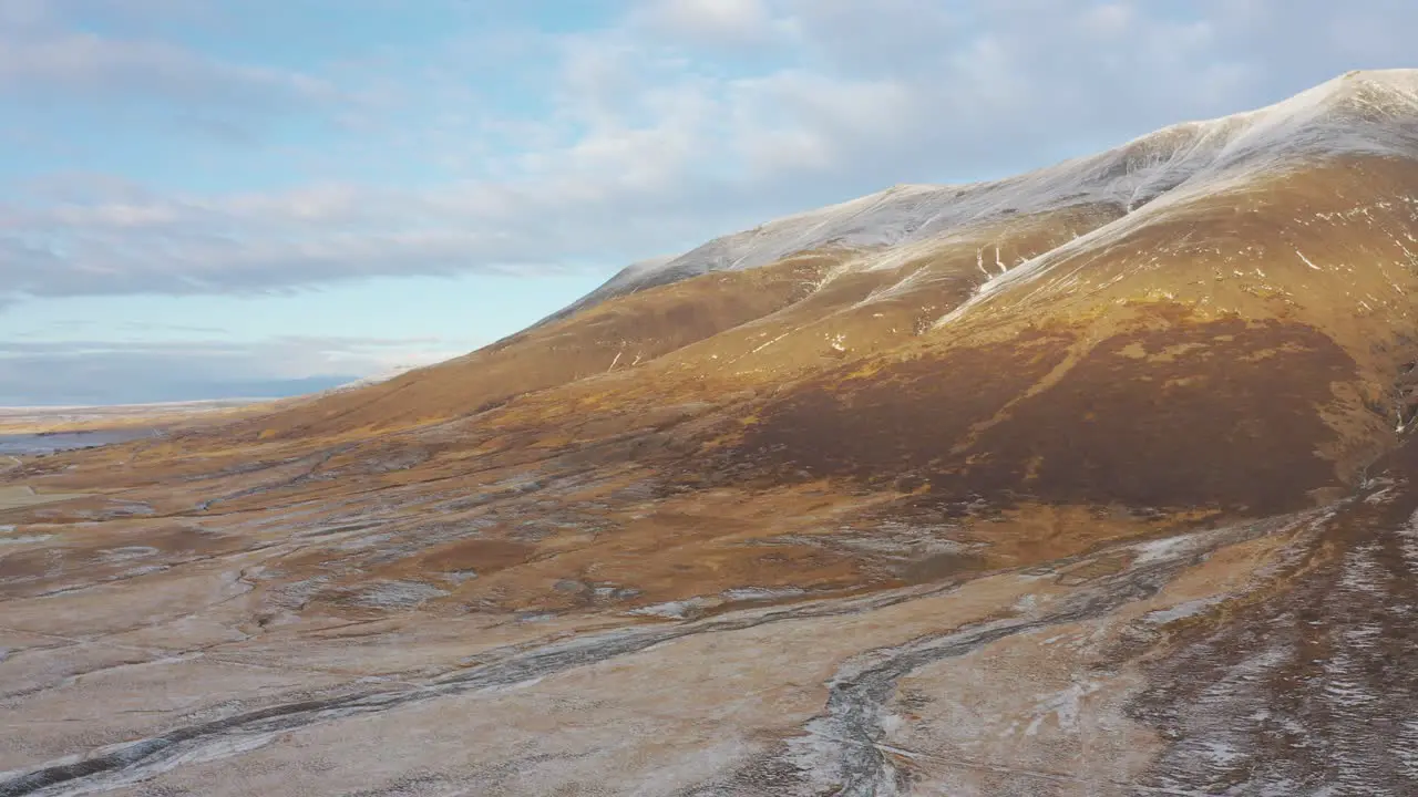 Iceland scenic aerial view of snowy mountain panning towards frozen delta river sunset