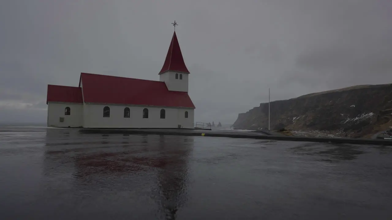 Approaching to Vík i Myrdal Church on Hill Above Sea and Coastline of Iceland on Dark Cloudy Rainy Day