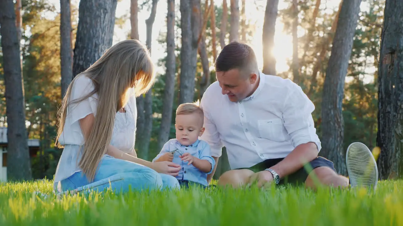 Portrait Of A Young Happy Family Mom Dad And Baby Boy Sitting On The Lawn Near His House At Sunset S