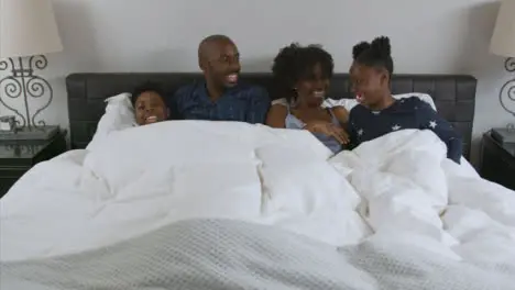 Parents Young Children Snuggle with Them In Their Bed