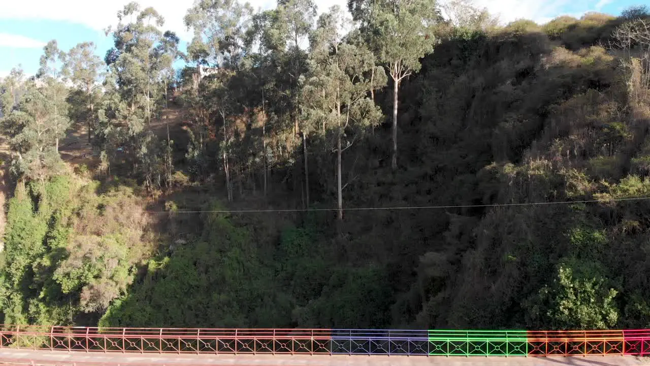 Dron pass colored bridge of Guambi towards trees on Ecuador