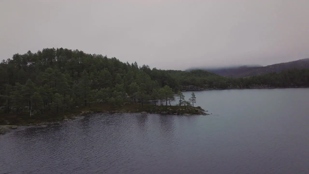 Aerial view of thick fog and cloud covering a forest and lake in Norway