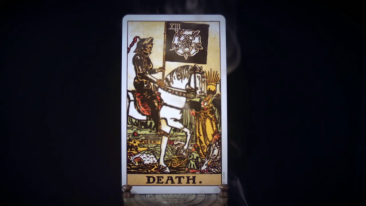 A tarot death card sits on a brass stand as smoke rises around it