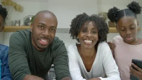 Joyful Family Listening and Laughing Directly into Webcam During Video Call