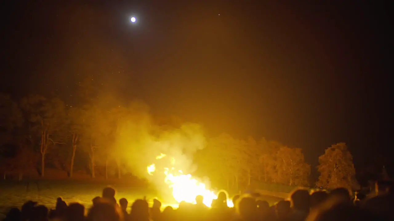 People gathered around fire in the dark during a full moon