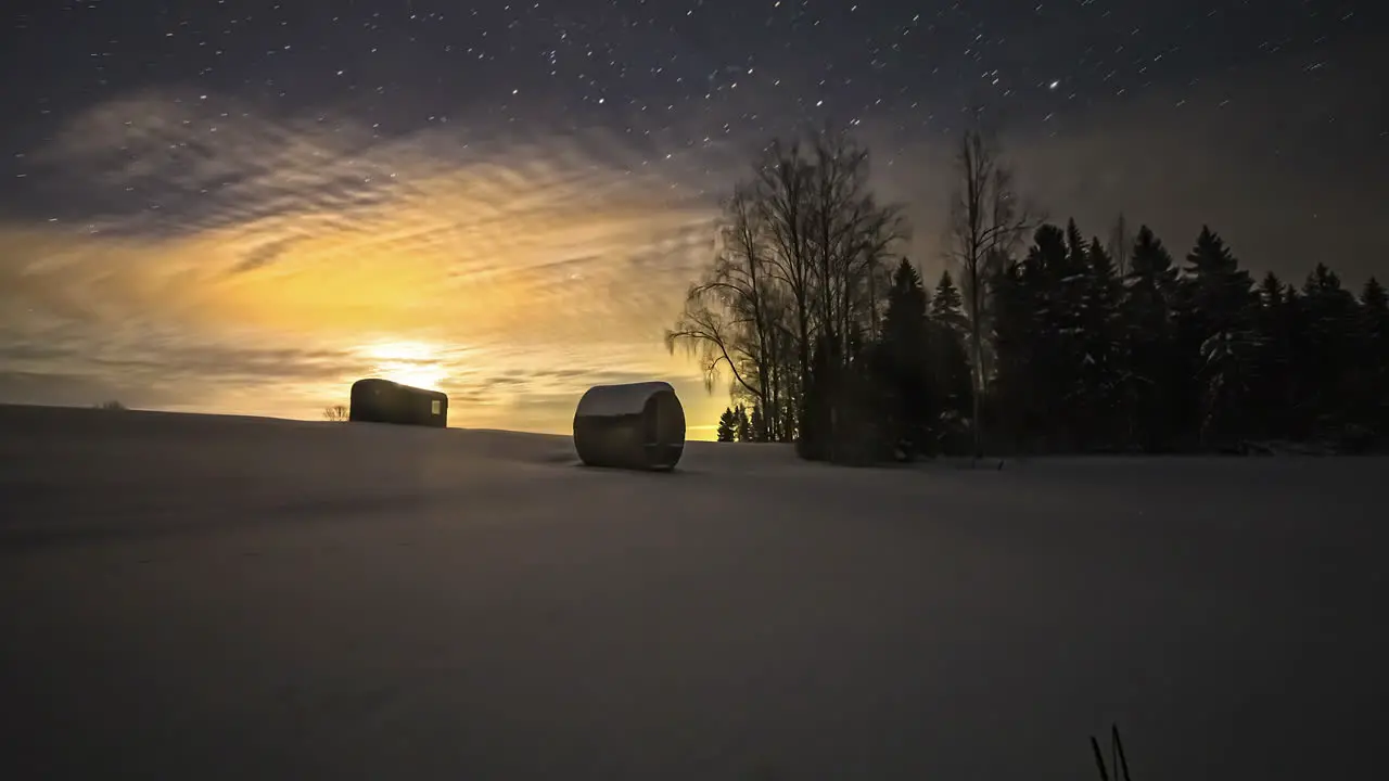 Amazing timelapse of starry night with highlighted full moon light in a ice covered wide land with forest and container cabin house in Lithuania