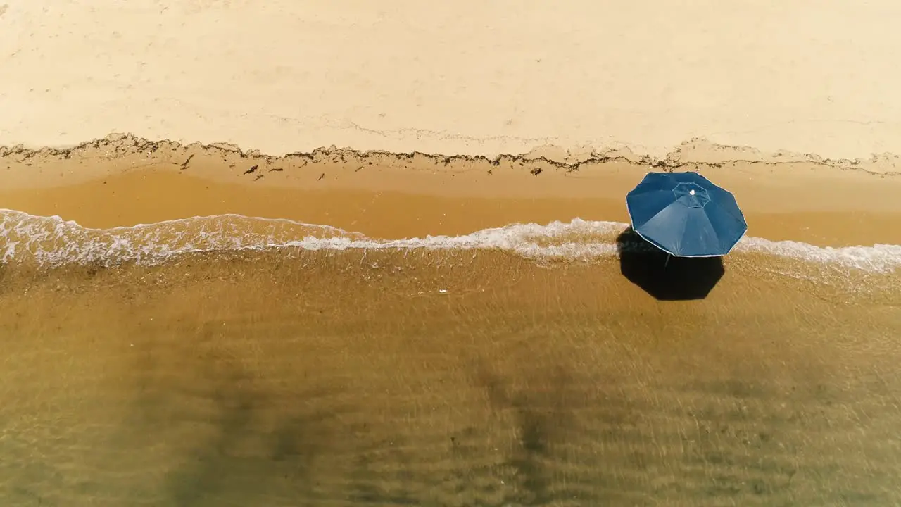 Aerial top down drone view of lonely sun umbrella in a deserted orange sand beach