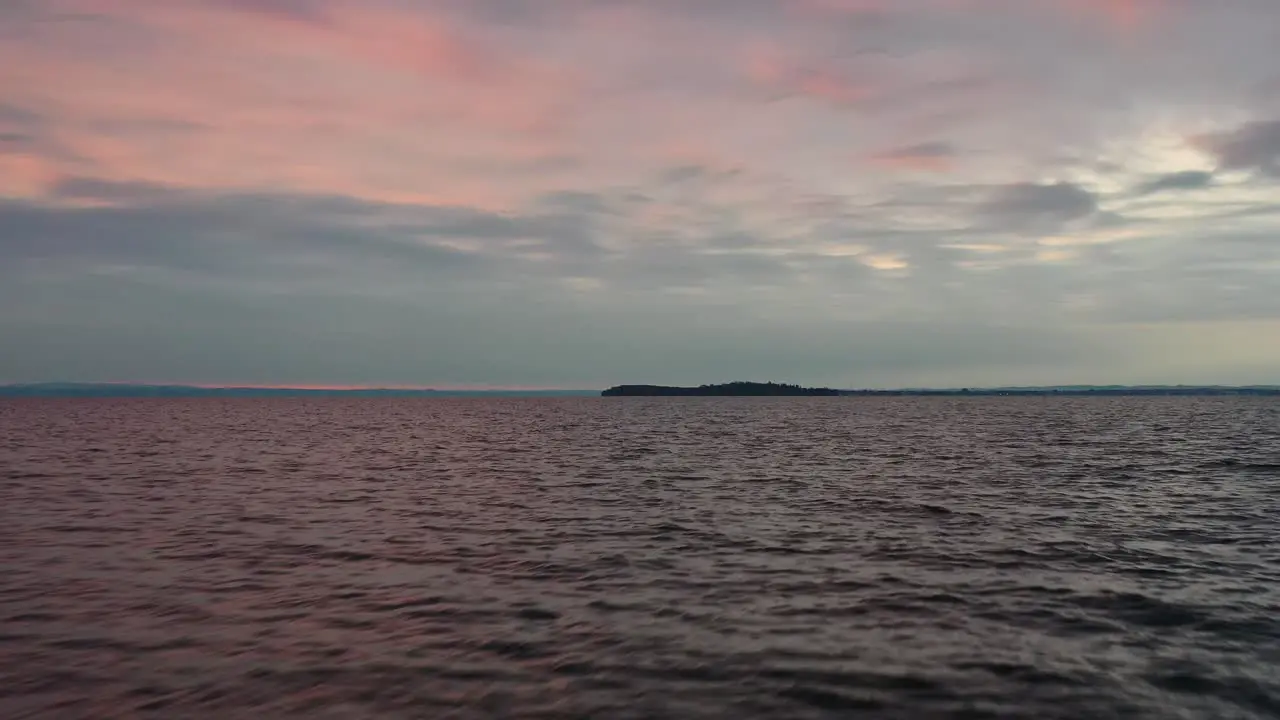 Cinematic Drone aerial flying over the water revealing pink sunset