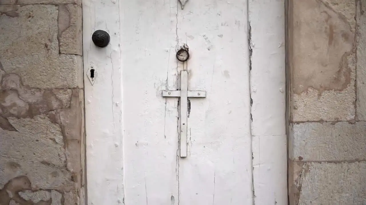 Aged white door with cross of stone building