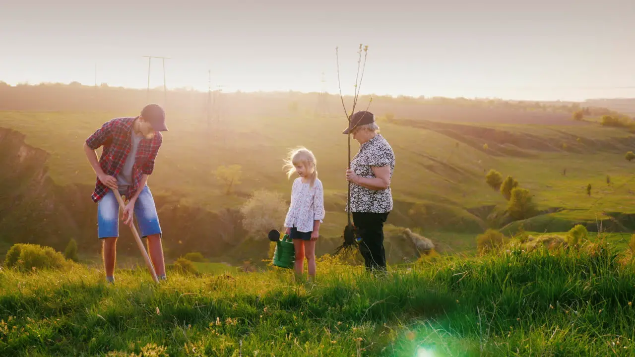 An Elderly Woman With Two Grandchildren A Boy And A Girl Plant A Tree Together