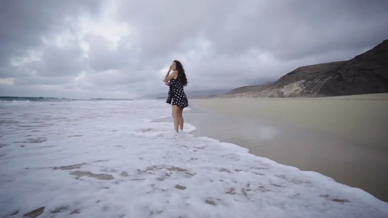 Multiracial mixed race young latin woman walking alone on ocean sand beach in Fuerteventura canary island Spain creative photographer exploring new touristic spot