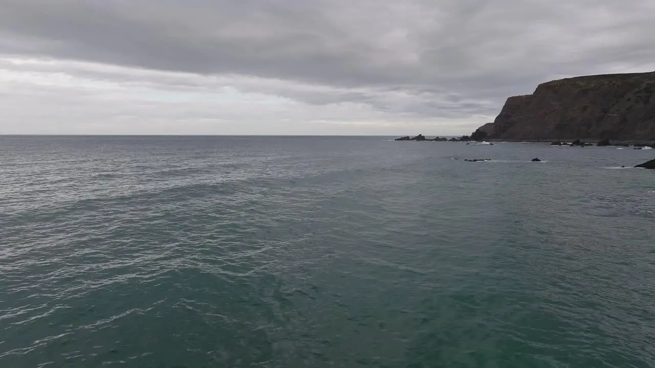 Drone flying over ocean at the Algarve Coast in Portugal during overcast day