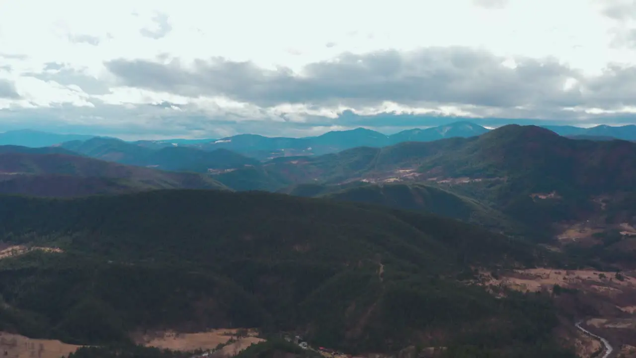 Slow aerial flyover of a temperate mountain range on a cloudy day