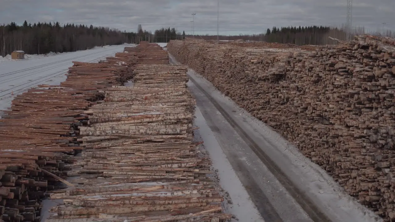 Cinematic aerial tracking shot over stacked timber in the snow