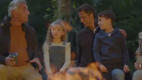 Long Shot of Father Grandfather and Two Kids Sitting by Campfire