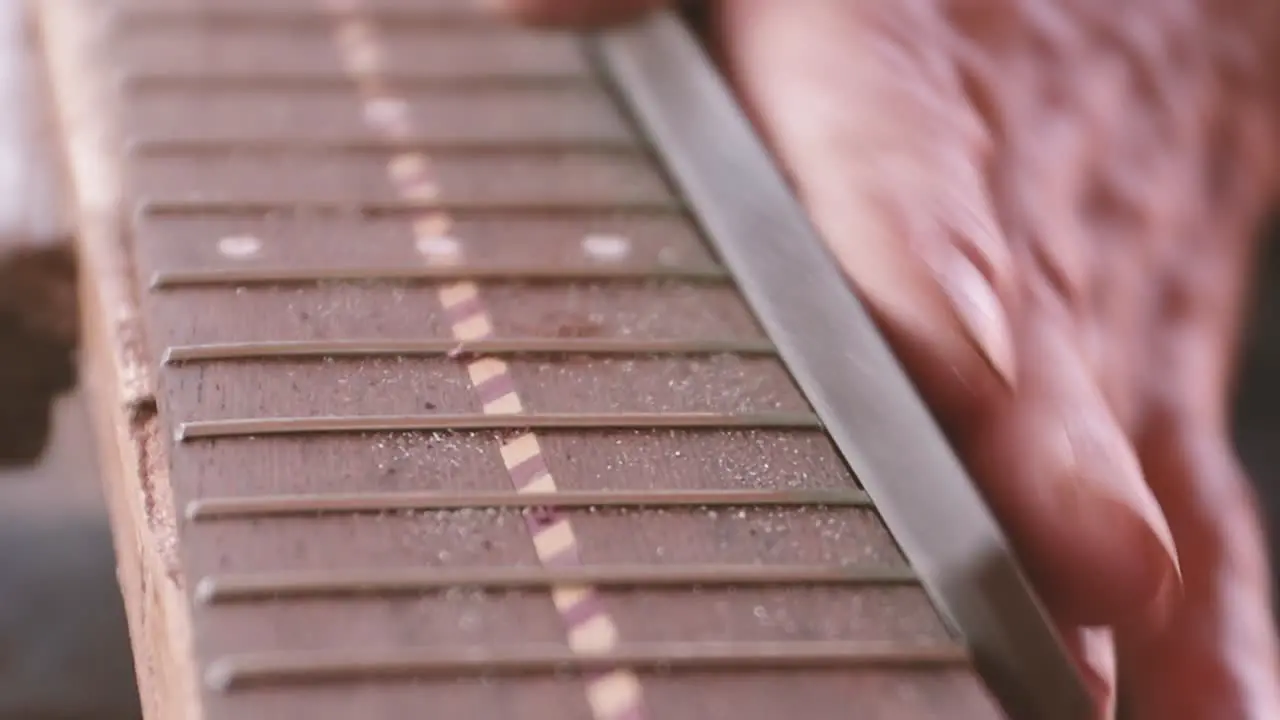 Luthier files frets on neck of classical guitar in Madeira Portugal