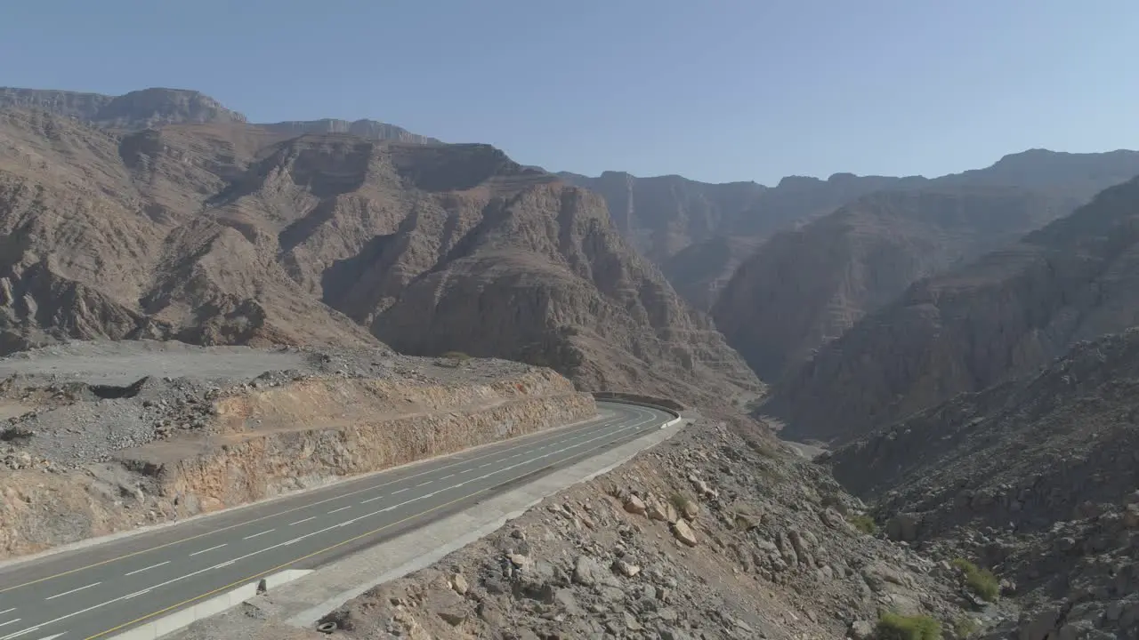 Cineamtic drone sliding shot of a road with a rocky mountain