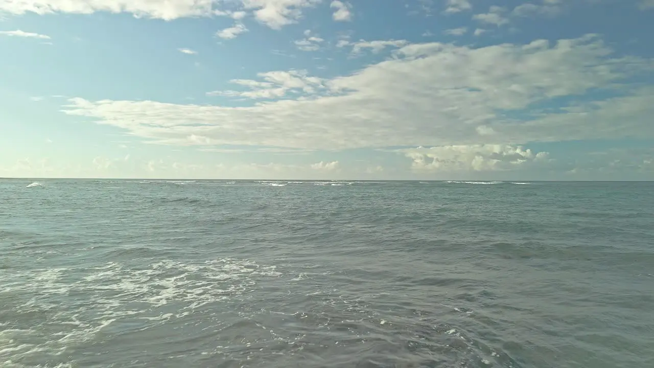 Low sweeping aerial view of rocky beach skimming above ocean waters