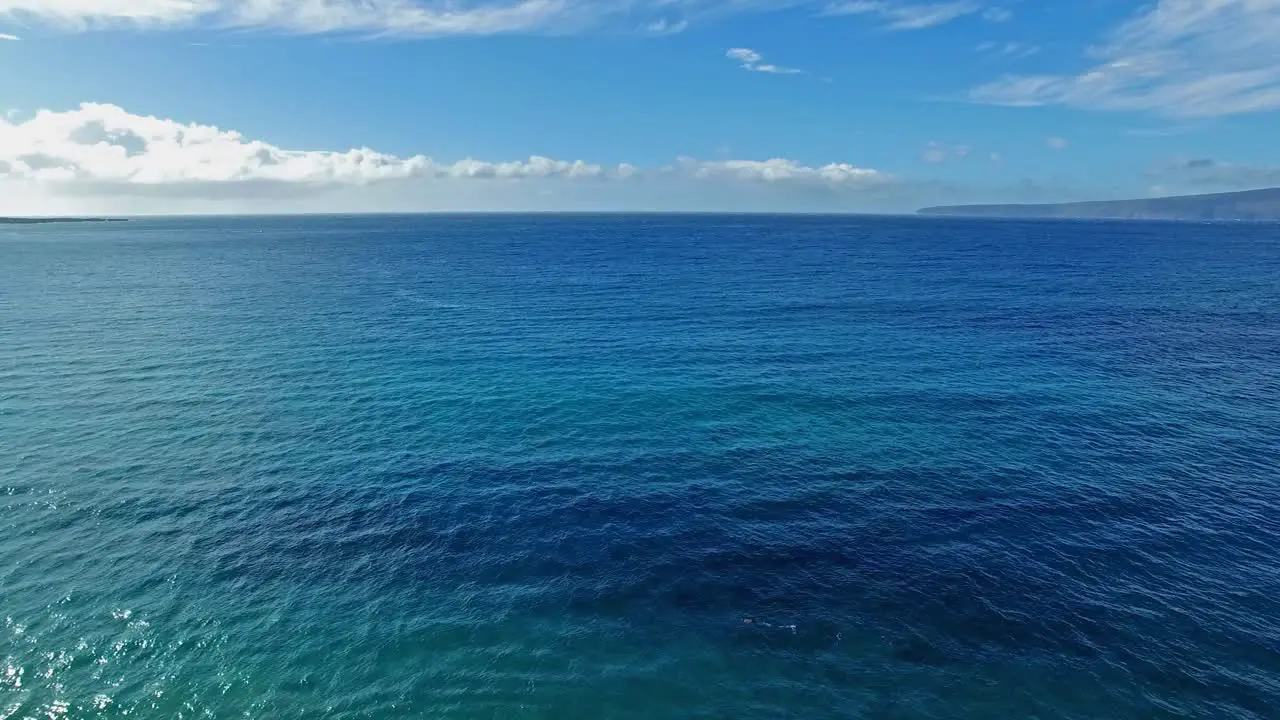 Panning aerial shot of a snorkeler in Maui Hawaii with beautiful blue water and land in the background