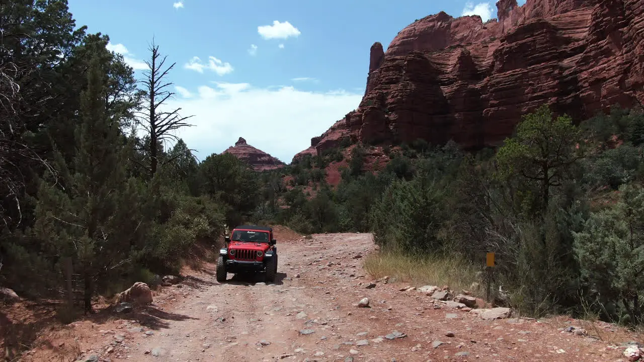 Aerial view of a jeep driving on a dirt road in middle of mountains of Sedona USA