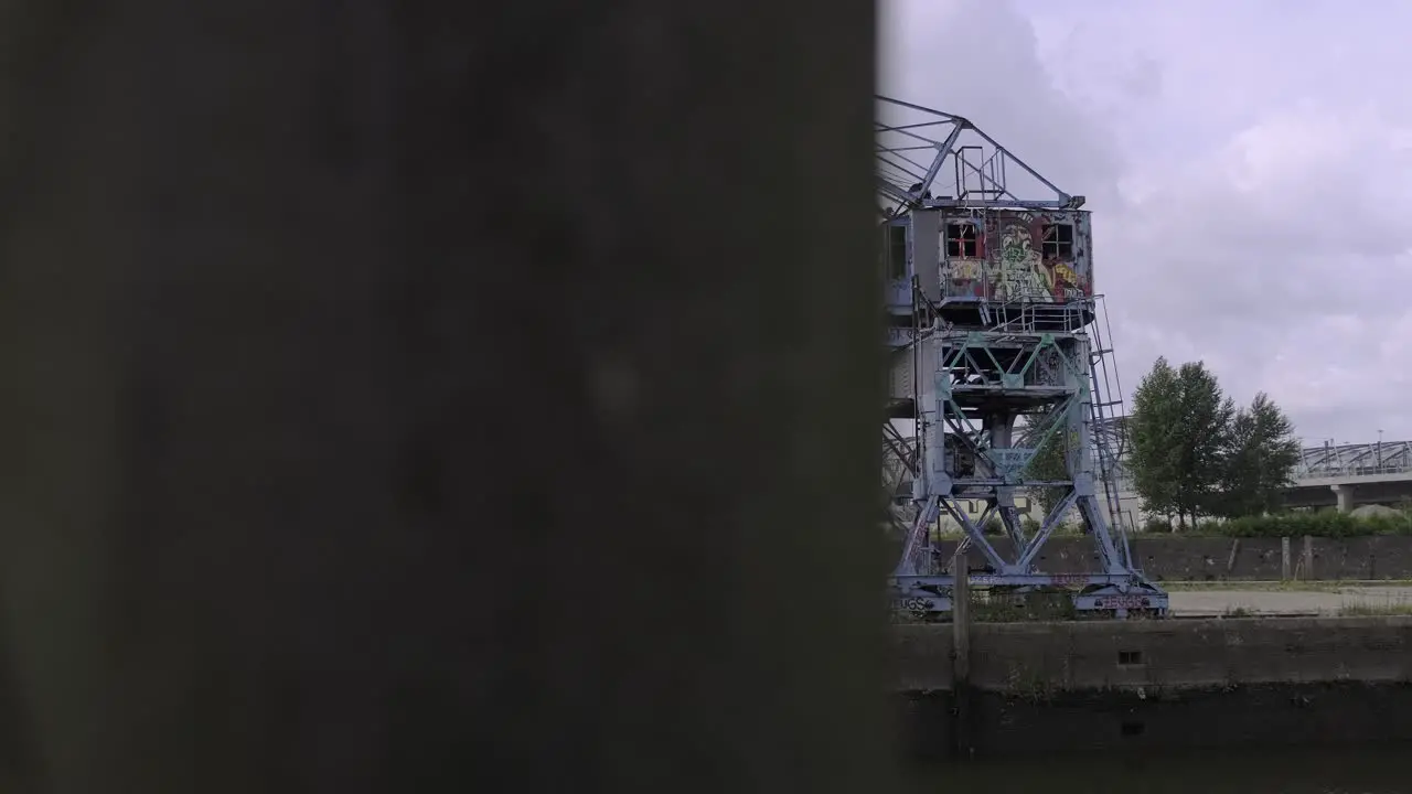 Pan right view of weathered metal crane located on quay against overcast sky in city