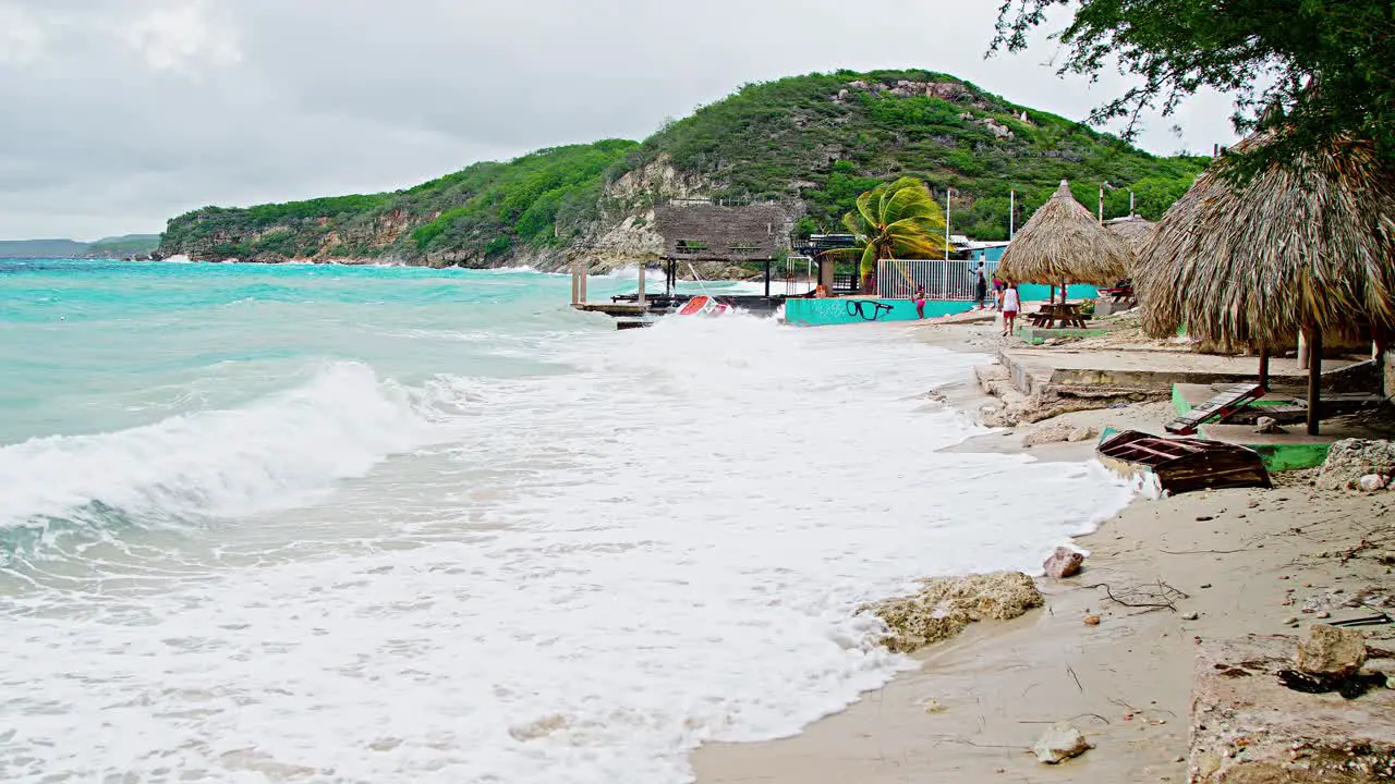 Wide shot of local wooden fishing boat being smashed into land during sudden storm with rough waves Caribbean