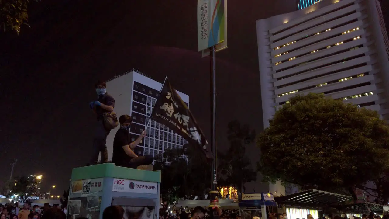 Protesters sitting on top of a telephone booth waving "Liberate Hong Kong" flag during the Oct rally Hong Kong