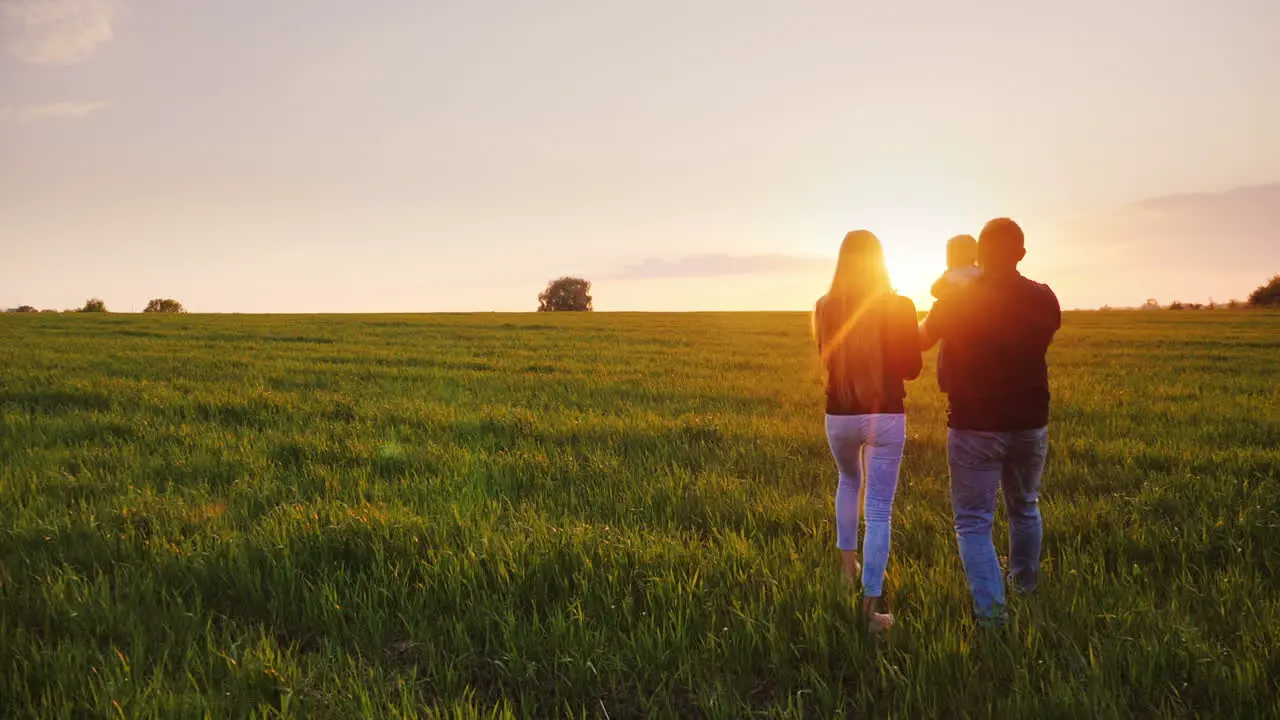 A Young Married Couple Is Walking Along A Beautiful Meadow At Sunset 3