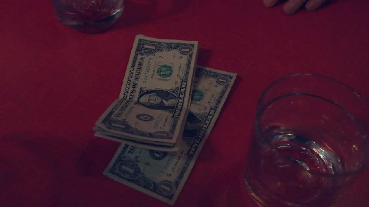 Money sits next to a drink on a red table