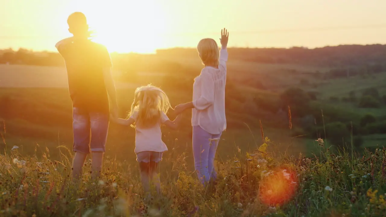 Young Energetic Mother Jumping With Her Children And Enjoying The Last Rays Of The Setting Sun