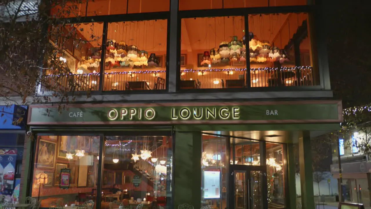 Low angle night view of illuminated Oppio Lounge Bar beside a street of Altrincham city in England