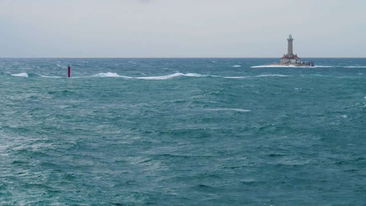 Lighthouse Porer and cardinal mark under strong south wind and waves on stormy weather restless sea