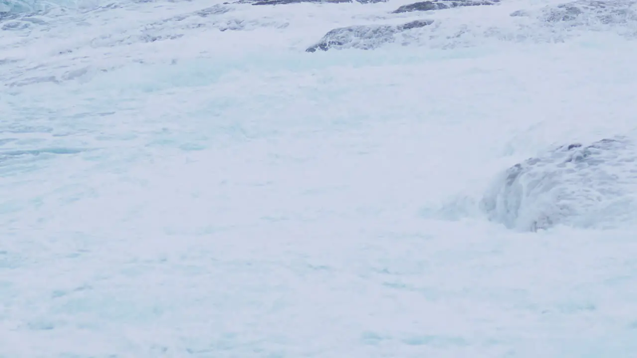 Big sea waves covering rocky shore creating foam and mist