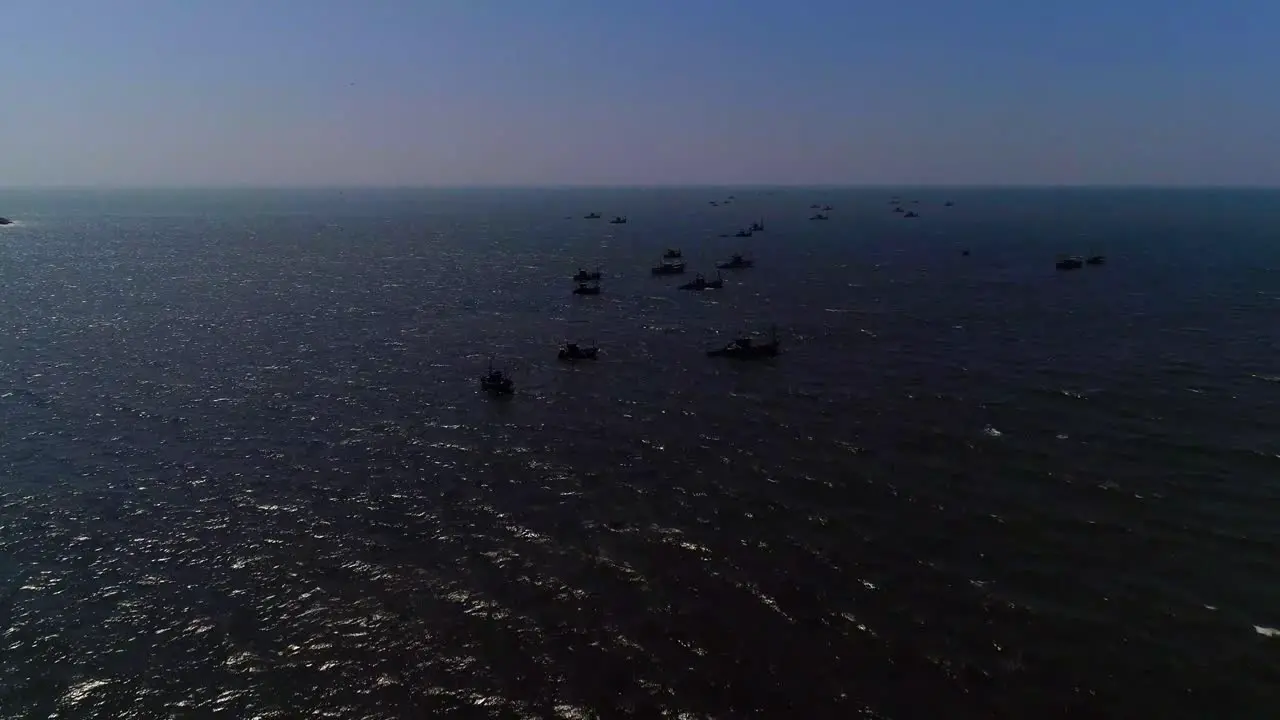 Drone footage moving towards a group of fishing boats in open sea