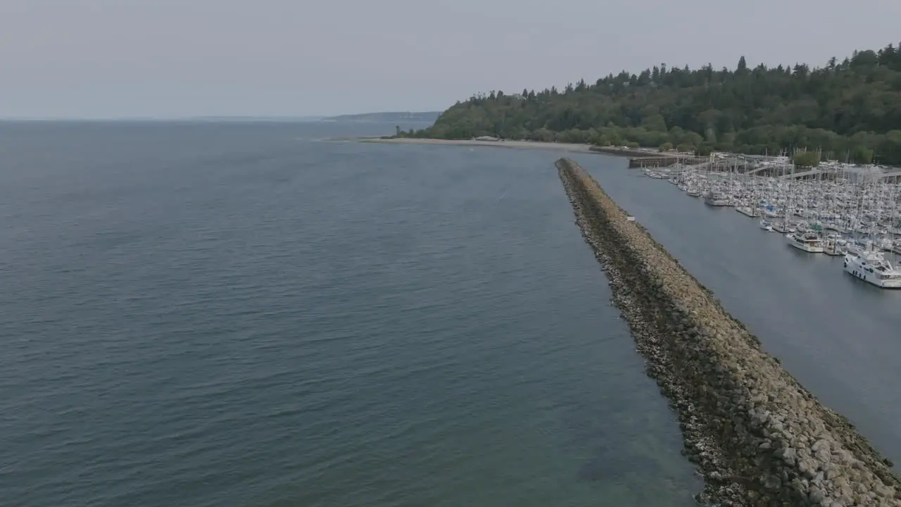 Slow aerial pan to the right over a rock barrier revealing a large leisure boatyard