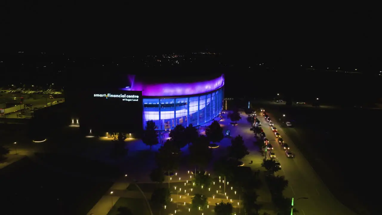 Drone shot circling the night lit Smart Financial Centre at Sugar Land TX USA