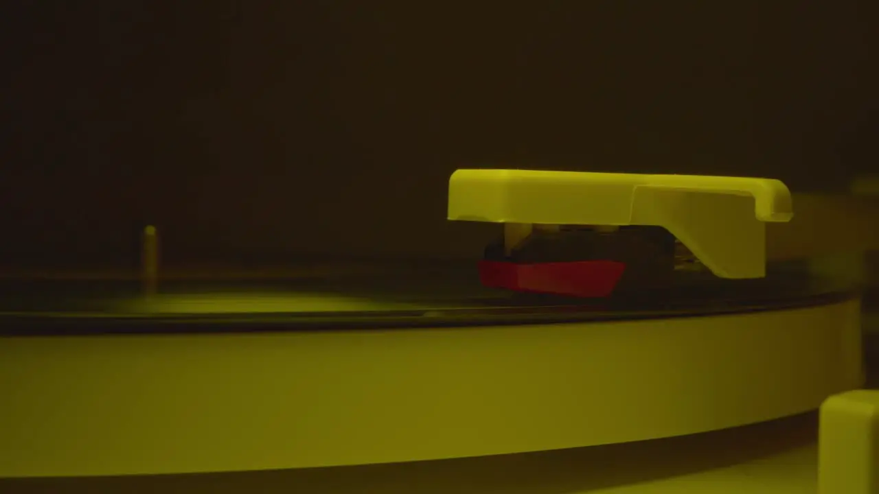 Record player needle dropped into groove of a record with slow blinking disco lights 