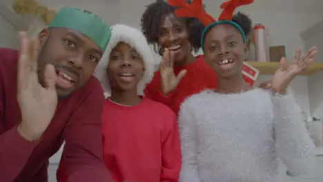 Joyful Family Waving Hello and Talking into Webcam During Christmas Video Call