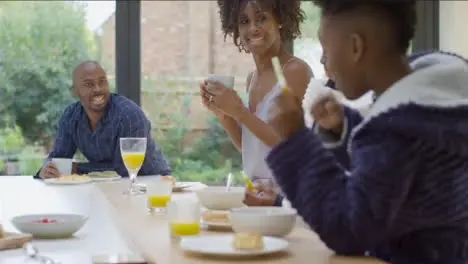 Family Talking and Laughing Together Over Breakfast