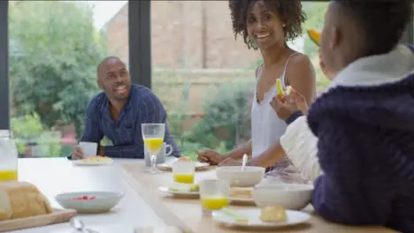 Family Talking and Laughing Together Over Breakfast at Kitchen Island