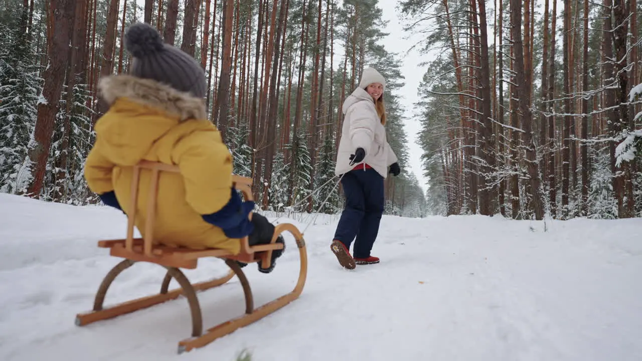 Eine Glückliche Junge Frau Geht Mit Ihrem Kleinen Kind Im Winterwald Spazieren Ihr Sohn Sitzt Im Holzschlitten