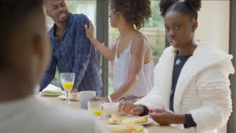 Family Talking and Laughing With Each Another Over Breakfast at Kitchen Island