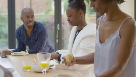 Young Daughter Butters Her Croissant During Family Breakfast