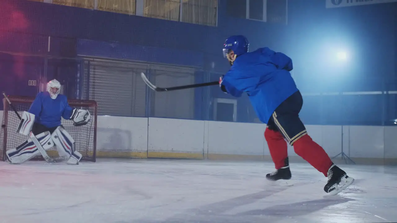 Delantero De Hockey Que Lleva Un Disco Patinando Junto A Un Defensa Contrario Y Dando Una Bofetada Al Portero Que Impide Marcar Un Gol Atrapando El Disco